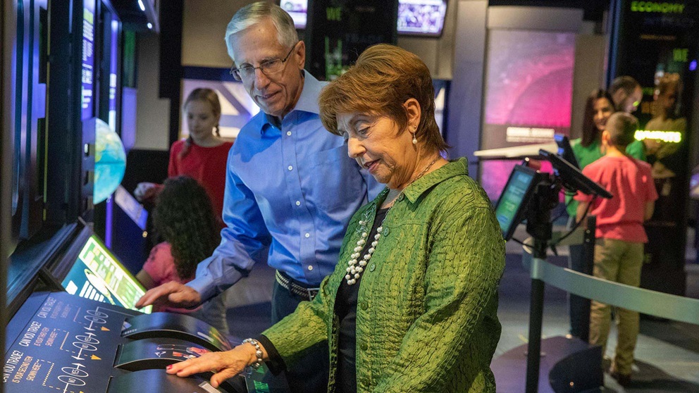 An older couple interact with a display.