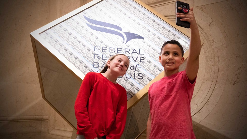 Two kids taking a selfie at the Museum's money cube exhibit